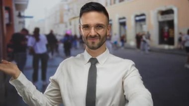 İspanyol bir adam şehir sokaklarında beyaz gömlek ve gözlük takmış, kendine güvenen bir gülümsemeyle şehir yaşamını gözler önüne seriyor..