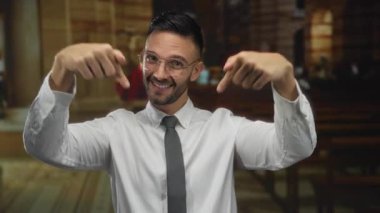 Gözlüklü genç adam kilisenin içinde aşağıya doğru gülümsüyor, sıcaklığı ve hoş geldin enerjisi yayıyor, bulanık dini içgüdüler ile çevrili, inanç ve toplanma öneriyor..