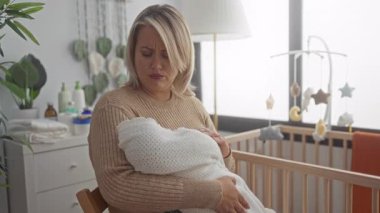 Sarışın kadın, beşikte beşikte beşiği beşikte, beşikte beşiği bembeyaz lambayla ve saksı bitkisiyle nazikçe yakar..