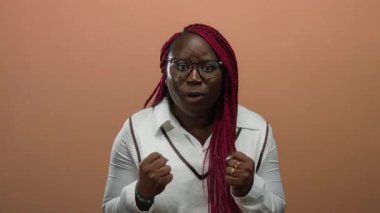 Kadın, kahverengi duvar arkasında neşeli bir ifadeyle başarıyı kutluyor