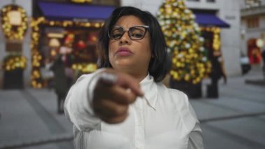 Şen şakrak bir şehir ortamının etrafında Noel ışıklarıyla bir kadın beliriyor..