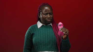 Elinde pembe kurdele tutan kadın canlı kırmızı arka plan göğüs kanseri farkındalığını sembolize ediyor..