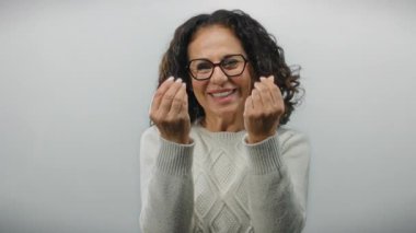 Kıvırcık saçlı, para kazanan kadın beyaz arka planda zenginliği, mutluluğu ve başarıyı ifade eden hareketler yapıyor..