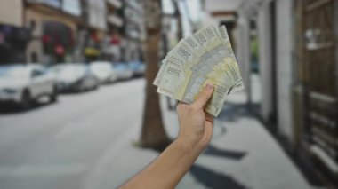 Bir şehir caddesinde Endonezya rupia banknotları tutan adam arka planda bulanık arabalarla açık bir şehir ortamında para gösteriyor..