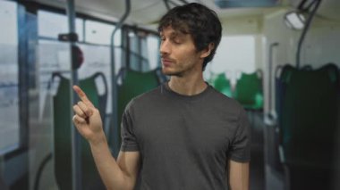 Genç adam işaret parmağını hareketli bir caddede hareket halindeki bir otobüsün içindeki boş yeşil koltuğa doğrultuyor; merak.