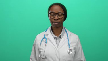 Steteskop ve gözlüklü beyaz önlüklü kadın doktor yeşil arka planda kameraya güvenle gülümsüyor profesyonel sağlık hizmetleri konseptine