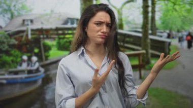 Uzun saçlı bir kadın, sokaktaki ahşap köprünün altında omuz omuza omuz silkiyor..