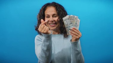 Mavi bir arkaplan önünde gülümseyen bir kadın, Peru banknotlarını tutuyor parmaklarıyla bir kalp hareketi sergiliyor, zenginlik ve mutluluk kavramını somutlaştırıyor..