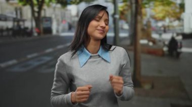 Canlı bir sokakta neşeyle dans eden genç bir kadın enerjik ruhunu ve neşeli ifadesini canlı bir atmosferle şehir ortamında sergiliyor..