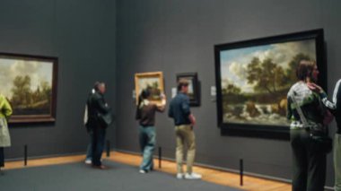 Müzede bulanık arkaplan resimlerini sergileyen insanlar ve kapalı alanda sanat eserlerini takdir eden ziyaretçiler..