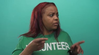 Yeşil gönüllü gömlekli bir kadın stüdyoyu işaret ediyor. Gözleri açık ve ağzı açık. Sürpriz..