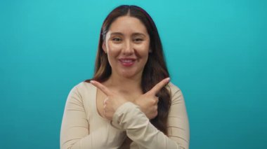 Stüdyoda işaret parmağıyla işaret eden İspanyol kadın gülümserken göğsünü işaret ediyor..