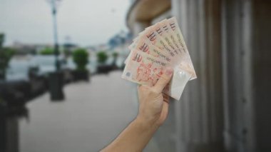 Şehir caddesinde tek başına dolar tutan bir adam, şehir hayatının ve açık havada yapılan finansal işlemlerin özünü yakalıyor..