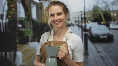 Şehir sokaklarında gülümseyen bir kadın, elinde kahve makinesiyle geziyor. Günlük kıyafetleriyle şehir yaşamını gözler önüne seriyor. Açık hava ortamını çağrıştırıyor..