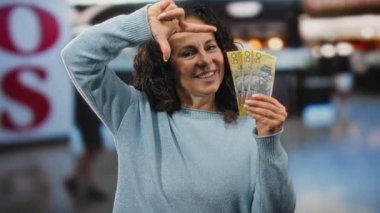 Avustralya dolarlarını alışveriş merkezinin içinde elinde tutan bir kadın kapalı alanda para gösteriyor orta yaşlı mutlu bir perakende satış ortamı.