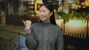 Mum ışığında bir kiliseyi işaret eden kadın dingin bir atmosferi olan çekici bir ifadeyi vurguluyor. İnanç ve güzellik temaları için mükemmel..