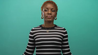 Stüdyoda çizgili süveter giyen bir kadın kendisine güvenir..