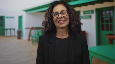 Dışarıdaki yeşil arka planda heyecanı ifade eden, duyguları ve şaşkınlığı temsil eden, canlı bir ortamda resmi kıyafetler giyen bir kadın..