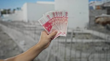 Bir inşaat sahasında İzlanda Krona banknotlarını tutan erkek el açık şehir ortamındaki mali işlemleri vurguluyor..