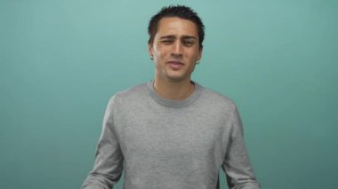 Kol saati takan İspanyol genç adam mavi stüdyo seti içinde ağlama hareketinde gözlere yumruk atıyor. Üzüntü..