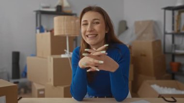 Yeni evinde gülümseyen bir kadın. Oturma odasındaki karton kutularla çevrili. Hareket halindeki heyecanı ve beklentileri somutlaştırıyor..