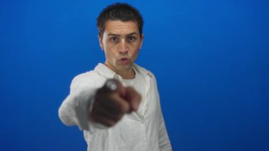 Beyaz tişörtlü genç İspanyol adam kamerayı çizik kaşlı ve stüdyoya dik dik bakan birini işaret ediyor; öfke..