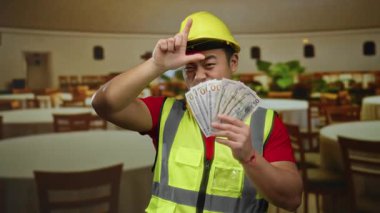 İnşaat yeleği ve kask giyen bir adam restoranda bize dolar kazandıran ezik jestler yapıyor..