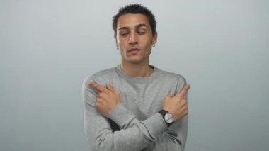 Stüdyoda gözleri kapalı gri kazak giyen genç İspanyol adam her iki tarafı işaret ediyor; belirsizlik..