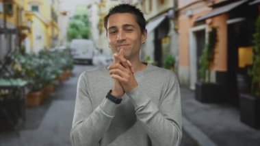 Genç İspanyol bir adam şehir sokağında dikiliyor. Bulanık bir şehir arka planında canlı ve canlı bir açık hava ortamı sergiliyor..