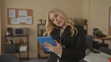 Modern ofiste birden fazla iş yapan kadın iş iletişimi ve üretkenlik için profesyonel ortamda tablet kullanırken telefonla konuşuyor.