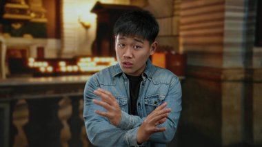 Tutkuyla kapalı alanda el kol hareketi yapan genç bir adam, dingin bir kilise geçmişine sahip, yoğun bir tartışma ya da vaaz verilmesini öneriyor..