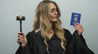 Üniformalı genç kadın yargıç Ukrayna pasaportu ve münferit beyaz arka plana karşı tokmak tutuyor.