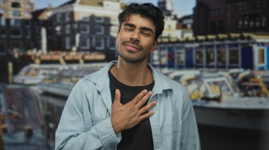 Tekneler ve rıhtımın yanında göğsü açık beyaz ceketli genç bir adam..