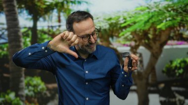 Olgun bir adam, açık hava parkında elinde arabanın anahtarlarıyla hayal kırıklığını ifade ediyor..