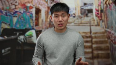 Renkli duvar yazıları çizili şehir arka planında gülümseyen genç adam, şehir atmosferini canlandırıyor..