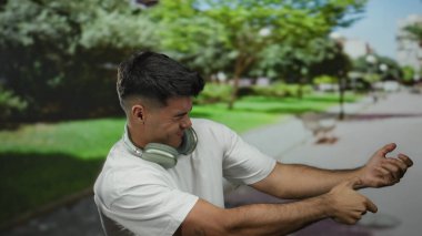 Parktaki genç adam, kulaklık takıp hayali bir halatı çekerek doğadaki dinamik bir anı yakalıyor..