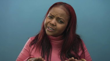 Kadın her iki avuç içini de stüdyoda omuz hizasında tutuyor. Mavi arka plan reddediyor. Sınır direnci meydan okuyor..