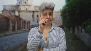 Sokakları gösteren çizgili tişörtlü, gri saçlı bir kadın. Belirsizlik yansıması..