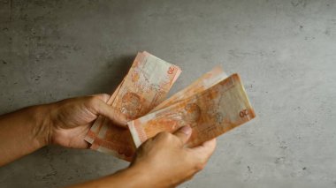 Filipinler 'de yerel para birimini vurgulayan somut bir arkaplan karşısında birden fazla Filipin pesosu tutan eller