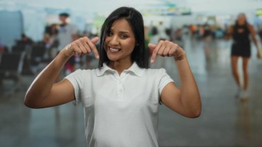Havaalanı terminalinde gülümseyen kadın arka planda bulanık gezginleri göstererek canlı kapalı bir seyahat ortamı yaratıyor.