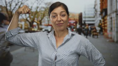 Bulanık yayalar ve araçlar arasında çıplak kollarını esneten orta yaşlı İspanyol kadın..