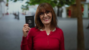 Gülümseyen kadın Amerika Birleşik Devletleri pasaportu tutuyor, hareketli bir şehir caddesinde duruyor, hareketli bir çevre ve gündelik bir atmosfer ile karakterize edilmiş, uluslararası seyahat temasını gözler önüne seriyor..