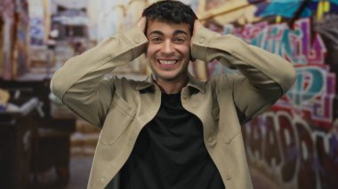 Genç İspanyol adam duvar yazısında kulaklarını elleriyle kapatıyor. Sürpriz heyecan..