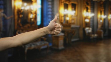 Zarif kilise içinde, sıcak ışıklandırmayla baş parmak gösteren bir adam dekoratif mimari detaylar ve lüks dekorasyonlar arasında olumlu bir jest yakalıyor..