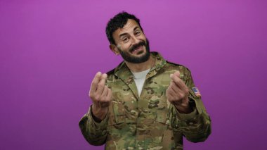 Askeri üniformalı İspanyol bir adam iki eliyle canlı pembe bir arka plana karşı para hareketi yapıyor..