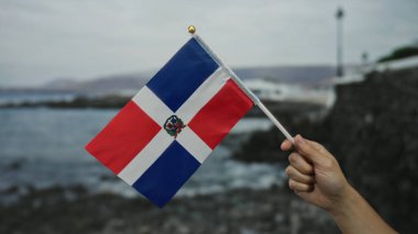 Sahilde Dominik Cumhuriyeti bayrağını taşıyan beyaz bir adam, açık havada vatansever bir ifade yakalamış..