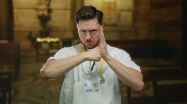 Sert ifadeli bir doktor, loş bir kilise ortamında boynuna steteskop takarak kavga eder..