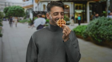 Waffle tutan adam gülen yüz ile şehir caddesinde el hareketi göstererek waffle; aşçılık neşe.