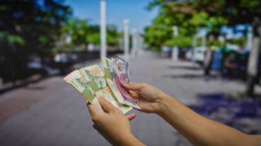 Şehir sokaklarında Hong Kong doları sayan bir adam, döviz kuruna ve açık hava ekonomik faaliyetlerine odaklı kentsel iş işlemlerini vurguluyor..