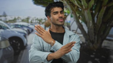 Kalabalık bir şehir caddesi sahnesinde kollarını kavuşturarak park etmiş arabaların ve ağaçların olduğu bir yerde, reddedilme.